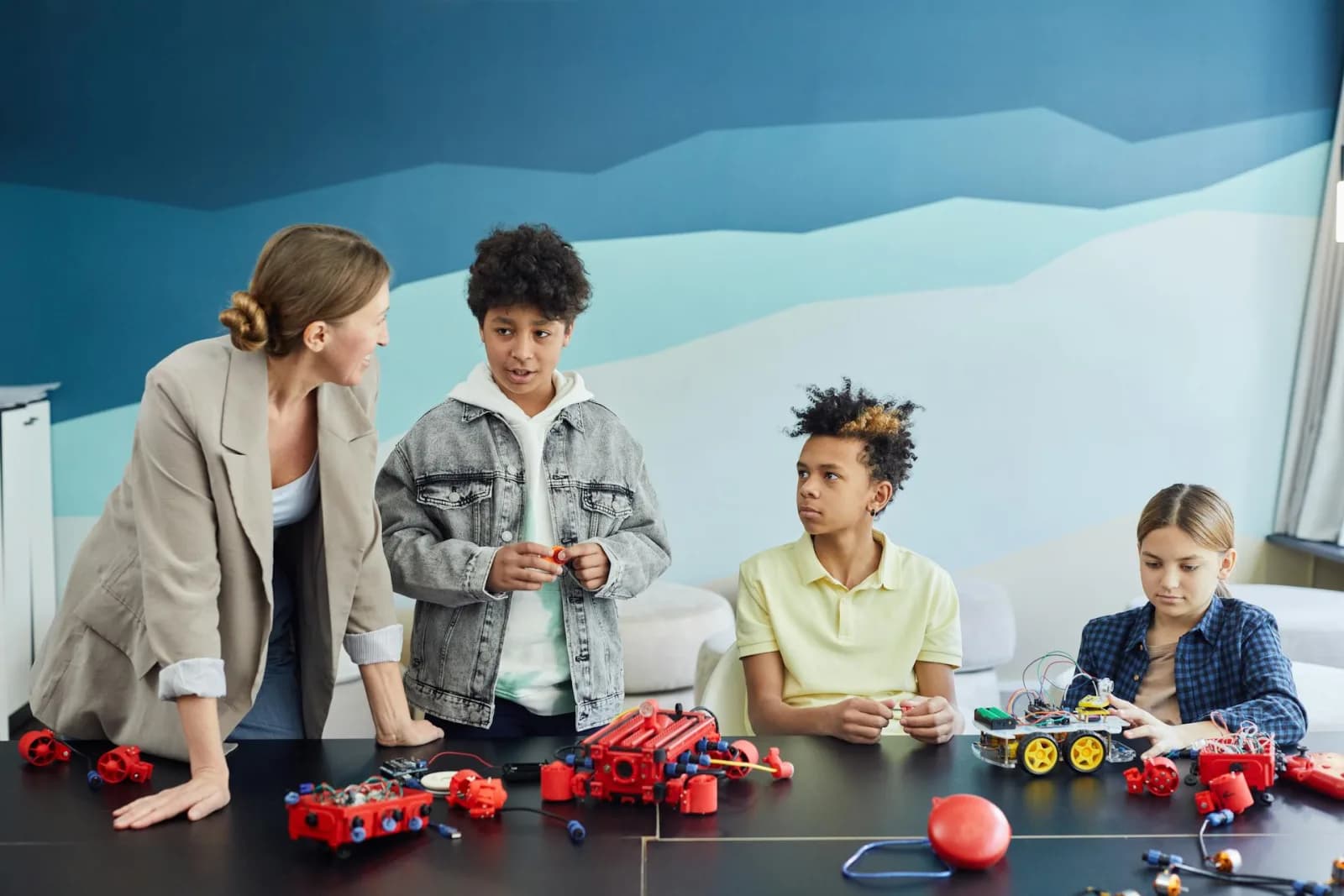 A teacher and three diverse students collaborating on a robotics project in a classroom