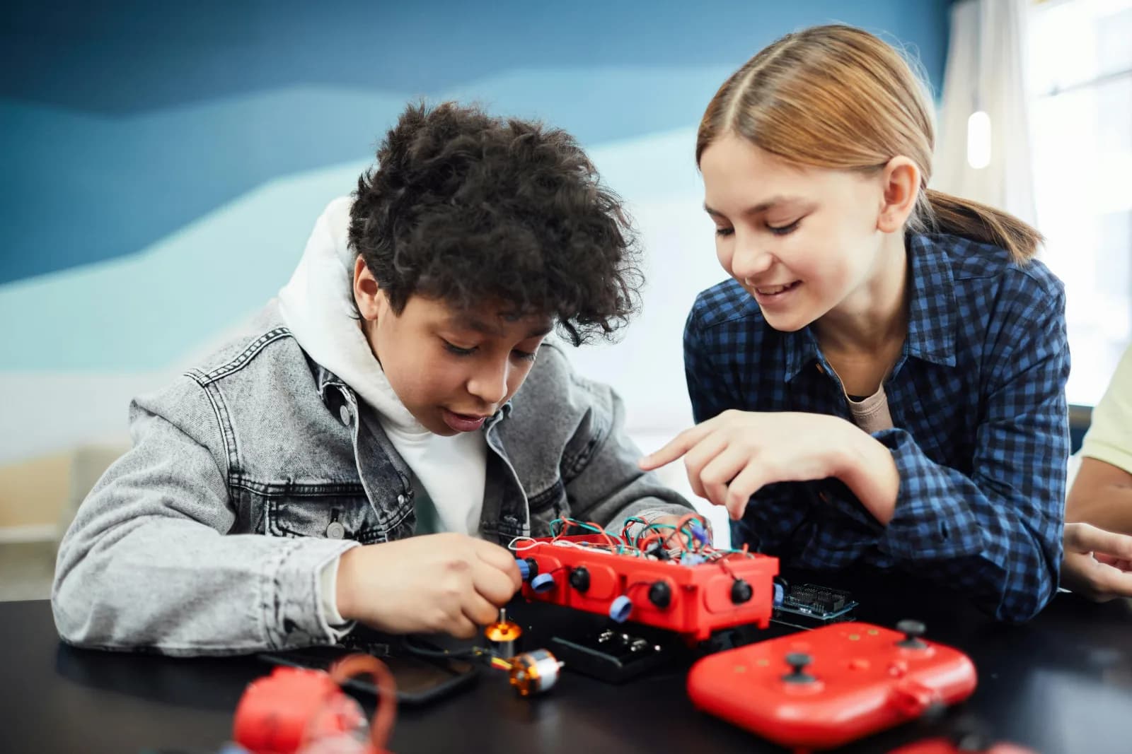 Two children building an electronic robotics kit with coloured wiring